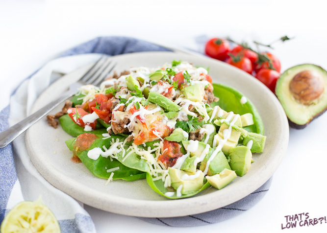 Image of Meal-Prep Low Carb Taco Salad on a plate with avocado, tomato, and sour cream drizzled on top.
