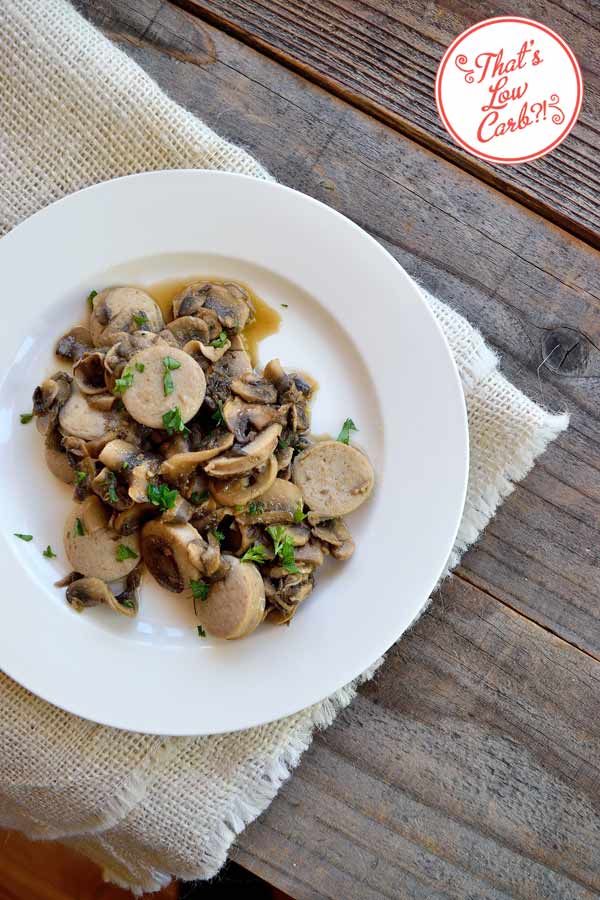 Low Carb Sausage And Mushrooms Recipe wit fresh parsley garnish on brown background