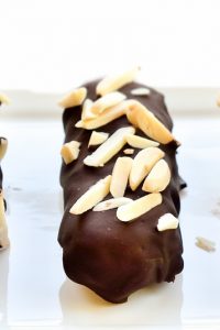 Image of three Keto Snack Bar covered in chocolate and peanuts lined up.