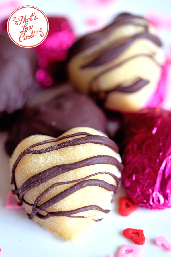 Low Carb Chocolate Covered Marzipan Hearts recipe with close up of marzipan heart with drizzled chocolate stripes across it.