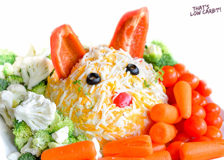 Image of low carb veggie dip shapped like a cat with red pepper ears, black olive eyes and tomato nose and assorted veggies.