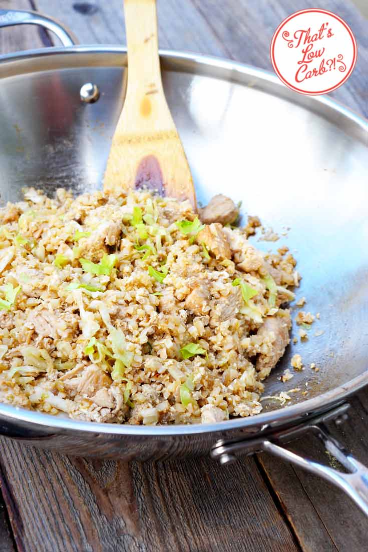 Low Carb Chinese Chicken Fried Rice Recipe shown in a stainless steel skillet with a wooden spoon resting on the side of the skillet.