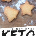PINTEREST IMAGE with words " 2 net carb keto cut out cookies" with image of keto cut out cookies on a wood cutting board and powder sugar sprinkled over top.