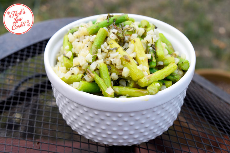 Low carb cauli-rice asparagus salad with tarragon dressing recipe shown from the side in a white bowl with the salad coming to a mound at the top of the bowl.