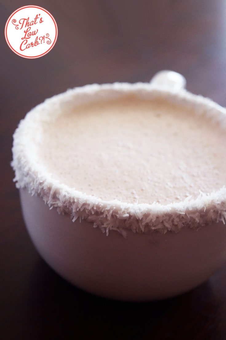 Low Carb German Chocolate Fat Bomb Hot Chocolate shown from the side in a white mug. The mug rim has been dipped in shredded coconut for a