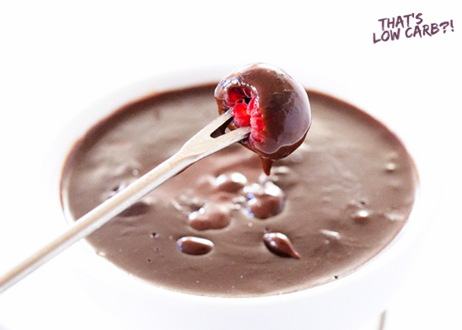 Low Carb Chocolate Fondue with a raspberry that has been dipped held over on a two prong fork.