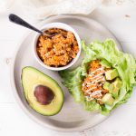 Overhead shot of Low Carb Buffalo Sloppy Joe in a white bowl and in a lettuce wrap with avocado and a half slice of avocado beside.