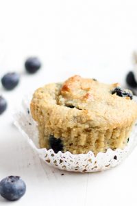 Low Carb Blueberry Muffins with blueberries spread around and a bowl of blueberries beside.
