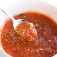 Image of Low Carb Homemade Salsa in a white bowl with a spoonful being lifted out.
