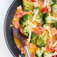 Image of Sundried Tomato Keto Salmon Dinner in a skillet with tomato and broccoli and orange sauce..