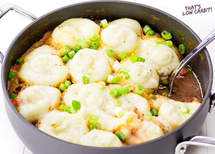 Image of Keto Low Carb Shepherd's Pie in a black skillet with one portion removed and green onion sprinkled on top.