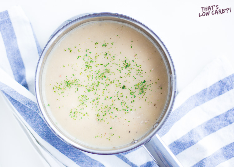Overhead shot of Low Carb Keto Sausage Gravy in a silver pot siting on a blue and white tea towel.