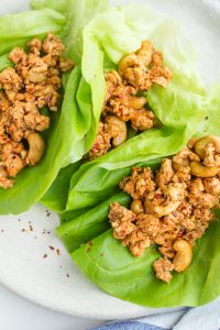 Overhead shot of Low Carb Cashew Chicken Lettuce Wraps opened up on a white plate.