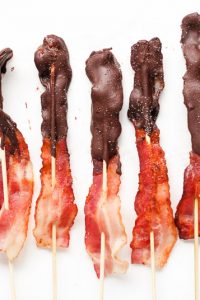 Image of Low Carb Chocolate Covered Bacon on skewers laying next to each other.