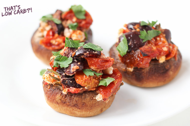 Image of three Low Carb keto Stuffed Mushrooms with olives, tomato. and feta on a white plate.