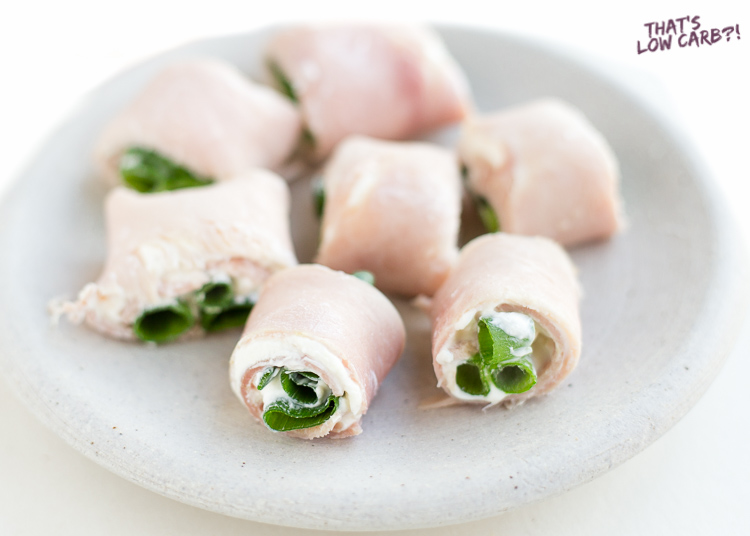 Image of Low Carb Ham Roll Ups Pinwheels on a white plate filled with cream cheese and green onion.