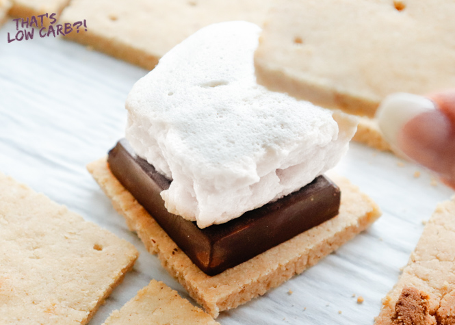 Image of Keto Marshmallows on top of a smore with another graham cracker being placed on top.