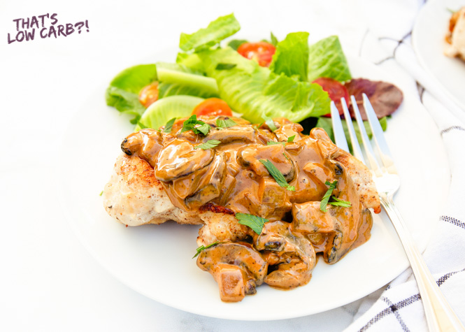 Image of Keto Fat Bomb Chicken with sauce and mushrooms and a side salad on a white plate.