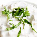 Close up shot of Keto Onion Dip in a white bowl with green garnish on top.