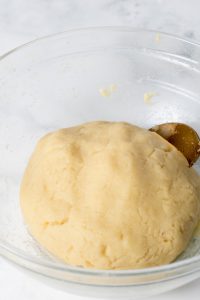 Image of keto Fathead dough prepared in a glass bowl with a bronze spoon laying inside.