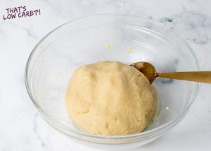 Image of keto Fathead dough prepared in a glass bowl with a bronze spoon laying inside.