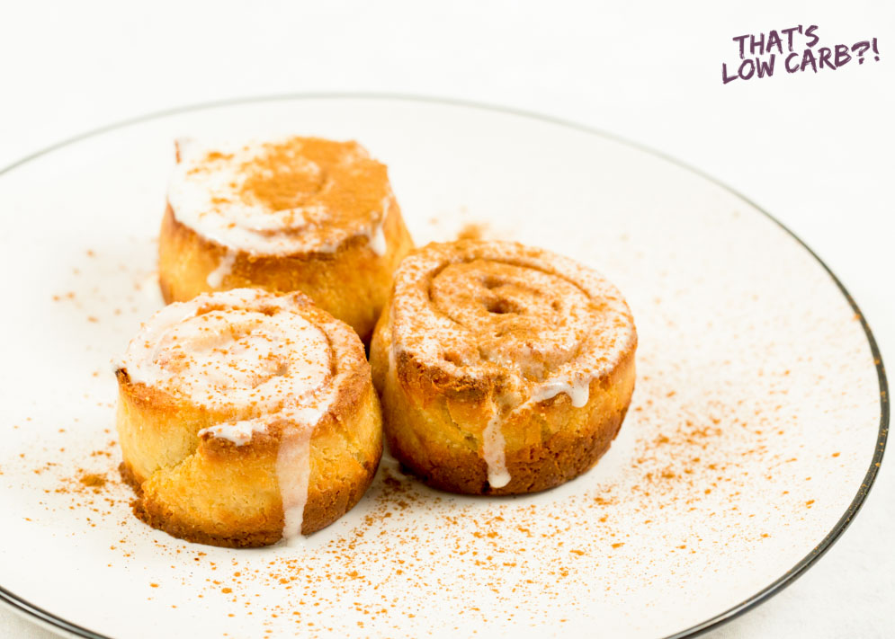 Image of three Keto Cinnamon Rolls on a white plate with cinnamon sprinkled over top.