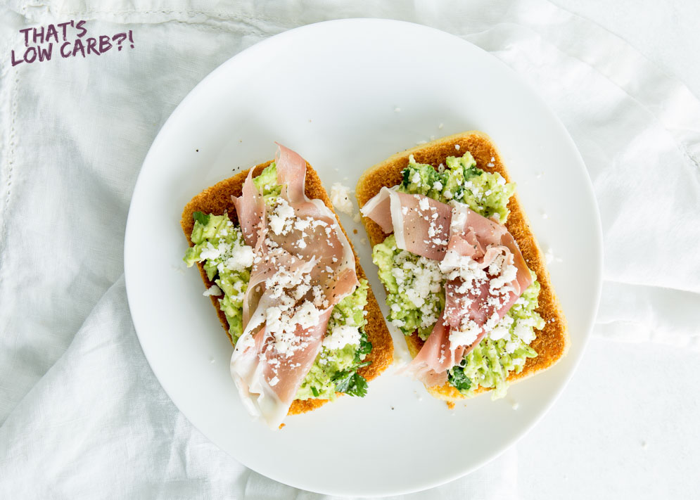 Overhead shot of 90 Second Keto Bread with avocado and prosciutto on top on a white plate.
