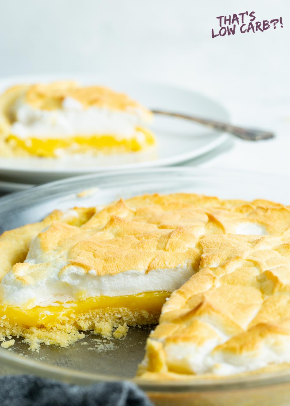 Picture of keto lemon meringue pie with slice take out of and slice of pie blurred out in background