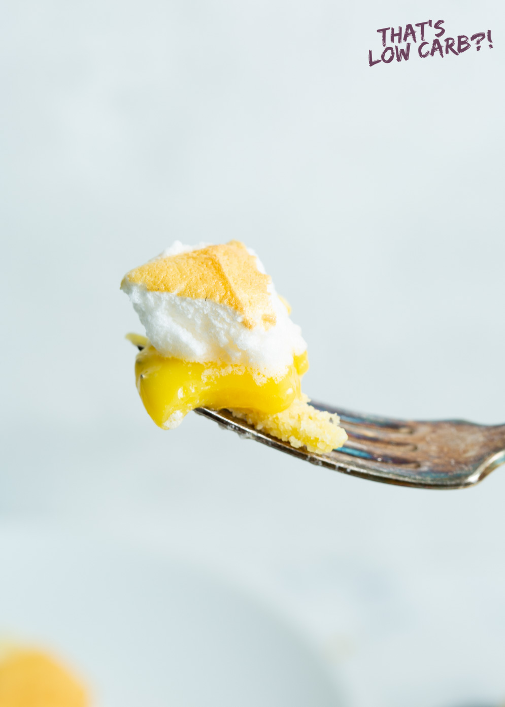 A bite of lemon meringue pie on a fork with white background