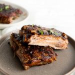 Pieces of cooked ribs stacked on top of each other on grey plate